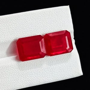 Może przedstawiać: Dwa czerwone szlifowane szmaragdowo kamienie szlachetne na białym tle.