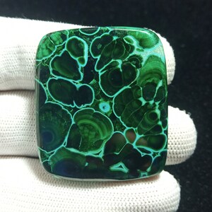May include: A square-shaped green malachite cabochon with a swirling, concentric pattern. The stone has a dark green color with lighter green accents.