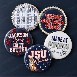 May include: Five circular pin-back buttons. One has a rhinestone border and text I LOVE THEE. One has a pearl border and text THANK GOD I AM A TIGER. One is navy with red text JACKSON GIRLS DO IT BETTER and red crystals. One is white with a barcode and text MADE AT Jackson State. One is navy with white dots, a tiger illustration, and text JSU Alumni.