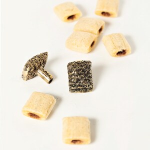 Peut inclure: Une variété de petites collations rectangulaires de couleur brun clair avec une garniture brun foncé. Il y a aussi deux petits objets texturés de couleur brun foncé.