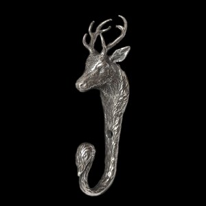 May include: A silver-toned metal wall hook shaped like a deer head with detailed antlers and fur texture. The neck of the deer extends downward to form a curved hook for hanging items, featuring a visible circular screw hole for mounting purposes.