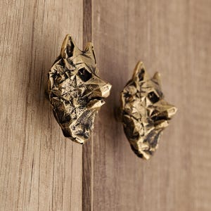 以下が含まれることがあります： 幾何学模様の金色の狼の頭の形をしたキャビネットノブが2つ