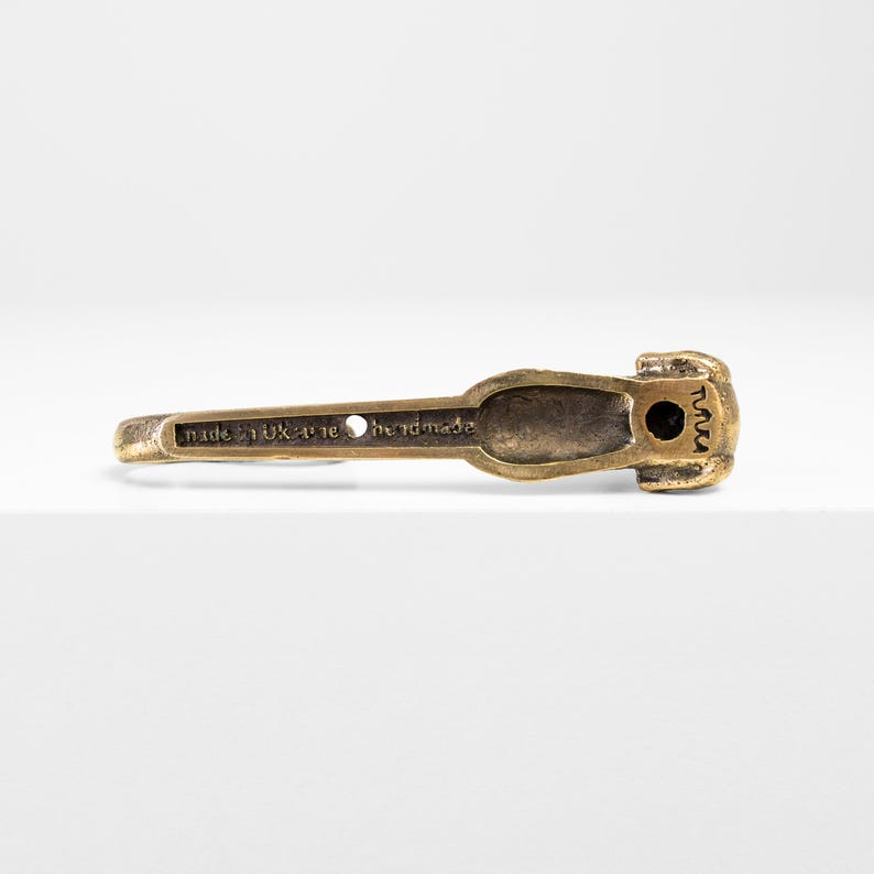 May include: A brass dachshund dog doorstop with the text "handmade" and "made in UK - 16" on the bottom.