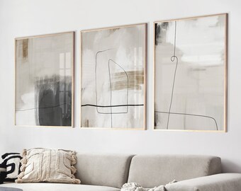 May include: A modern living room with a sectional sofa, a coffee table, and three abstract art prints on the wall. The sofa is beige and has a throw blanket draped over it. The coffee table is black and has a wooden top. The art prints are in shades of beige, brown, and black.