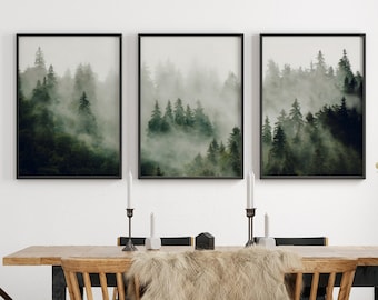 May include: Three framed prints of a misty forest scene hang on a white wall above a wooden dining table with black legs. The table is set with a faux fur throw, candlesticks, and two chairs. A wooden stool sits in the corner of the room.