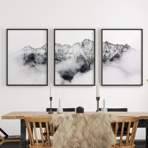 May include: A dining room with a wooden table and chairs, a faux fur throw, and three black framed prints of mountains with clouds.