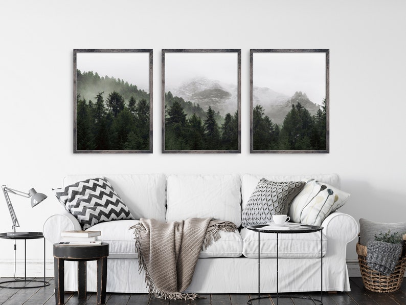 May include: Three framed photographs of a misty forest with mountains in the background. The photos are in black frames with a white mat.