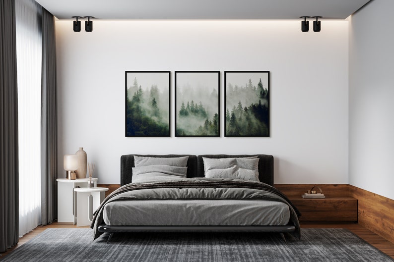 May include: A gray upholstered bed with a black frame and a gray blanket. Three framed black and white prints of a foggy forest scene hang above the bed.