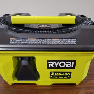 Könnte beinhalten: Ein gelber und schwarzer 3-Gallonen-Nass- und Trockensauger mit einem schwarzen Schlauch und dem Ryobi-Logo.
