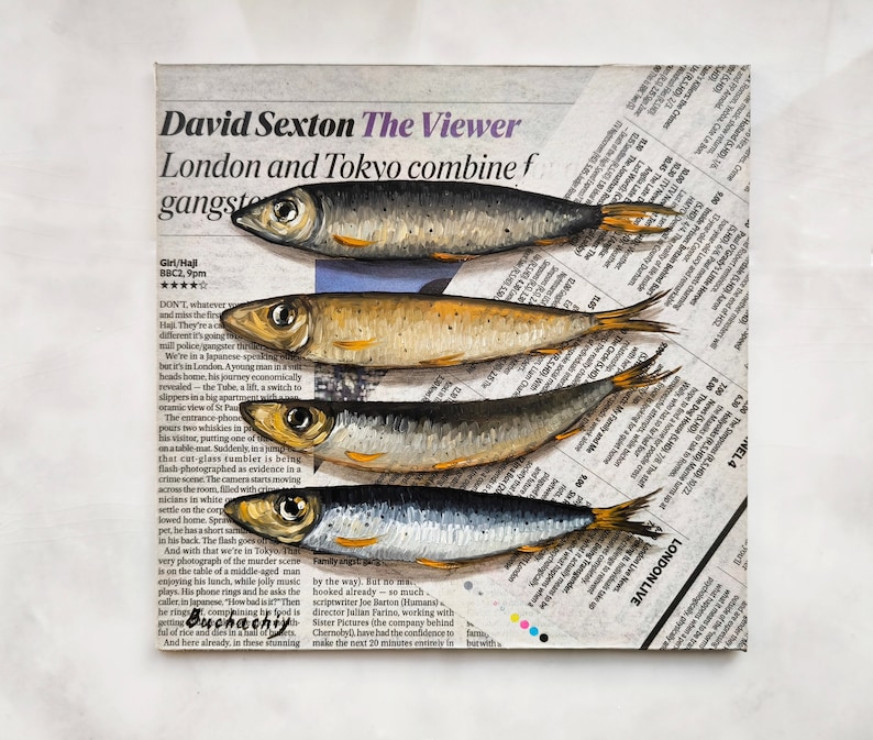 May include: A close-up of a newspaper clipping with the headline "David Sexton The Viewer" and the text "London and Tokyo combine f gangste" printed in black ink. Four silver fish are painted on the newspaper, with their tails extending off the edge of the page.