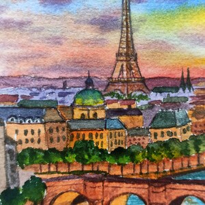 May include: Watercolor painting of the Eiffel Tower in Paris, France. The painting depicts the tower in the distance with a bridge and buildings in the foreground. The sky is a vibrant orange and pink sunset.