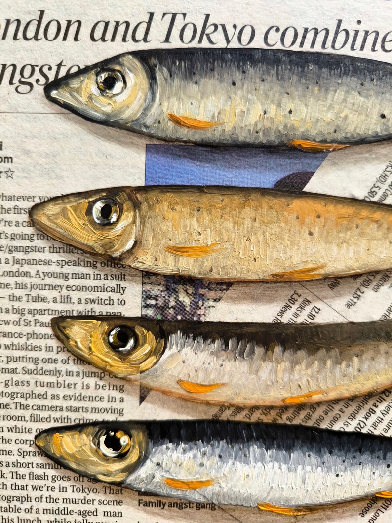 May include: A close-up of five painted fish, stacked on top of each other. The fish are painted in a realistic style, with details like scales, fins, and eyes. The fish are painted on a background of newspaper text, which is partially visible.