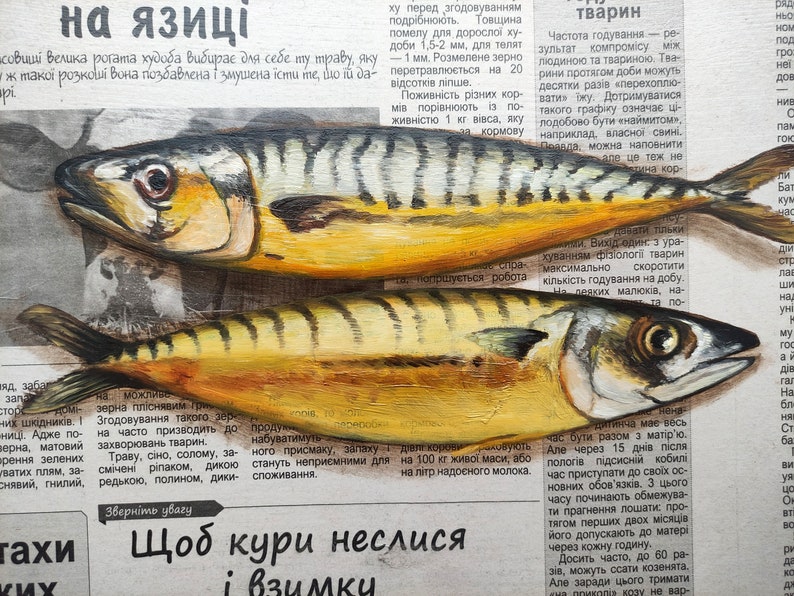 May include: Two painted mackerel fish on a newspaper background. The fish are yellow, silver, and black, with detailed scales and fins. The artwork is a realistic depiction of the fish, with visible brushstrokes and texture.