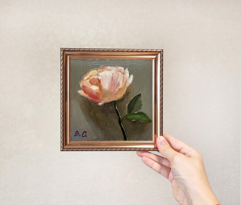 May include: A small framed painting of a single pink flower with green leaves on a dark green background. The painting is signed "B.O."