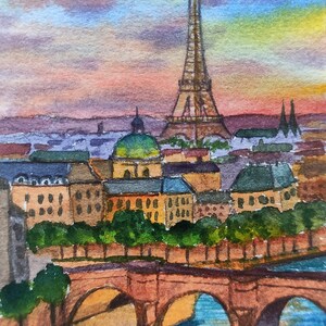 May include: Watercolor painting of the Eiffel Tower in Paris, France. The painting depicts the tower at sunset with a bridge and river in the foreground. The sky is a mix of pink, orange, and purple.