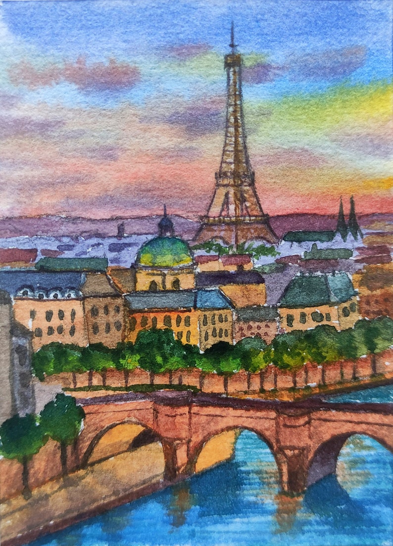 May include: Watercolor painting of the Eiffel Tower in Paris, France. The painting depicts the tower at sunset with a bridge and river in the foreground. The sky is a mix of pink, orange, and purple.