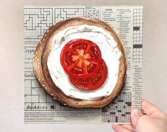 May include: A painting of a bagel with cream cheese and two slices of red tomato. The bagel is on a crossword puzzle background. The painting is held by a hand.