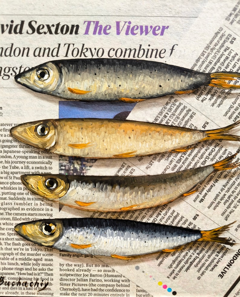 May include: A close-up of a newspaper page with a painting of five silver fish on top. The fish are arranged in a stack, with the largest fish at the bottom and the smallest fish at the top. The newspaper page has text about a gangster thriller and a Japanese-speaking man in a suit.