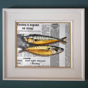 May include: A framed artwork featuring two mackerel fish painted over a vintage newspaper background. The fish have yellow and black stripes. The frame is white.