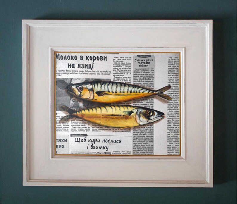 May include: A framed artwork featuring two mackerel fish painted over a vintage newspaper background. The fish have yellow and black stripes. The frame is white.