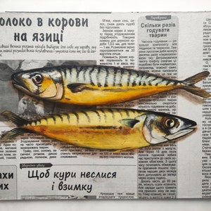 May include: An oil painting on a canvas of two yellow and black mackerel fish, with visible scales and fins, set against a backdrop of a Ukrainian newspaper. The text in the newspaper is in Ukrainian.