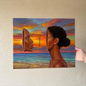 May include: An oil painting depicts a woman's profile with a key floating between her face and the other half of her head. The background shows a beach scene with a colorful sunset. The artwork is held by a person.
