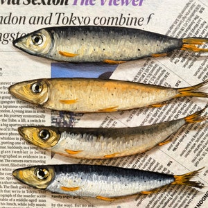 May include: A close-up of a newspaper page with a painting of five silver fish on top. The fish are arranged in a stack, with the largest fish at the bottom and the smallest fish at the top. The newspaper page has text about a gangster thriller and a Japanese-speaking man in a suit.