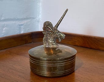May include: A brass trinket box with a unicorn head lid. The unicorn has a curled horn and detailed features.