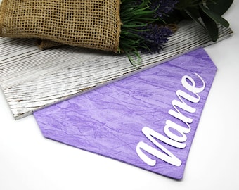 May include: Purple fabric dog bandana with the word "Mame" in white lettering.