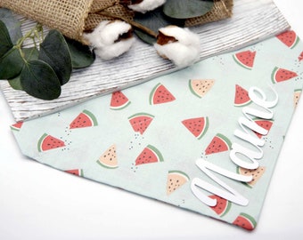 May include: A light blue bandana with a watermelon print and the name "Mame" written in white on it.