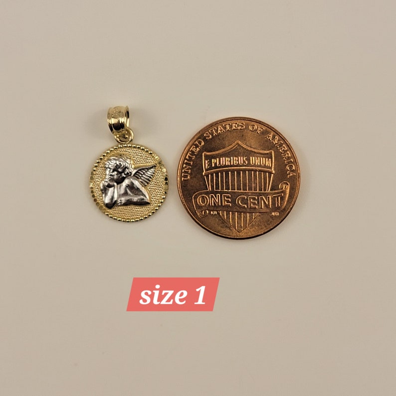 May include: Gold and silver angel pendant charm, shown next to a US penny for size comparison.  The pendant features a detailed angel with wings and a halo.