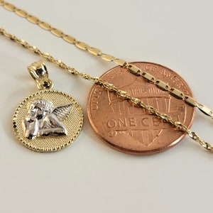 May include: A gold chain necklace with a small pendant featuring a two-tone angel design. The pendant is about the size of a US penny.
