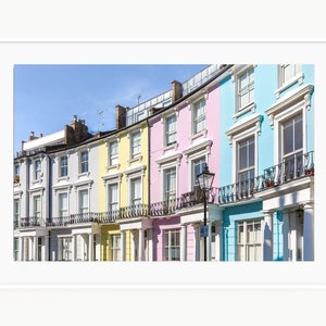 May include: A row of colorful houses in London, England. The houses are painted in shades of blue, pink, yellow, and gray. The houses have white window frames and black railings.