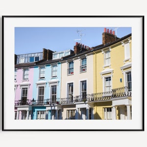 May include: A row of colorful houses with white trim and balconies. The houses are painted in shades of pink, blue, and yellow.