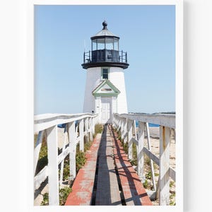 Vertical photograph of Brant Point Lighthouse in Nantucket, viewed straight down the weathered boardwalk with a bright blue sky and soft coastal light.