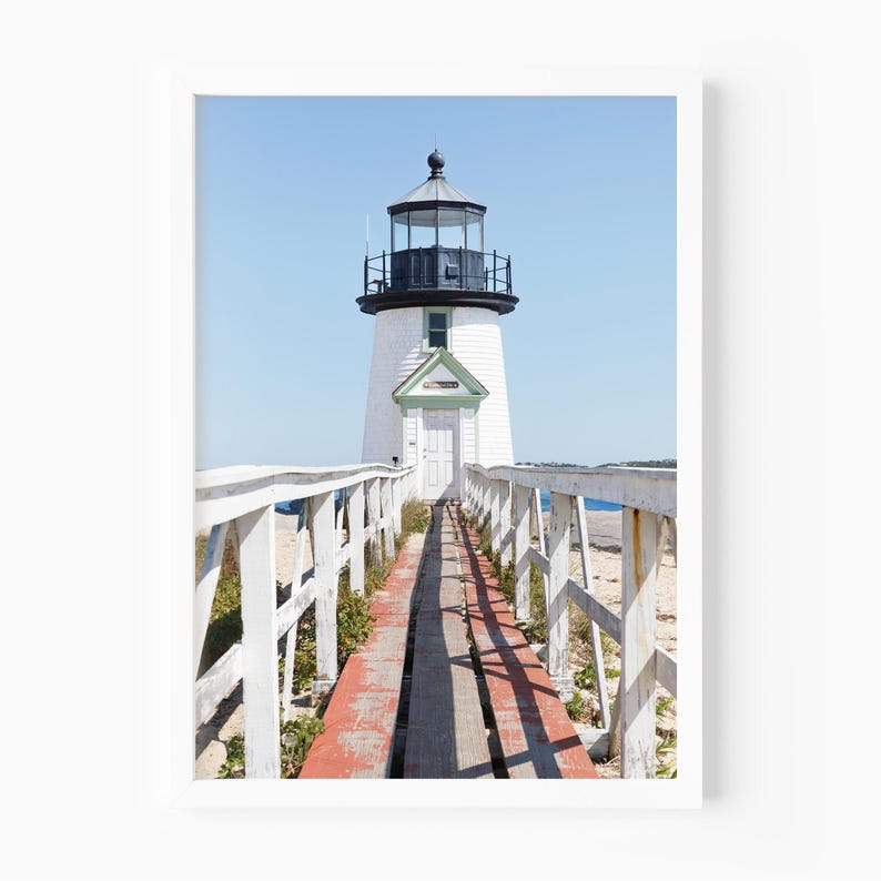 Vertical photograph of Brant Point Lighthouse in Nantucket, viewed straight down the weathered boardwalk with a bright blue sky and soft coastal light.