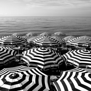 Black and white beach print featuring striped beach umbrellas taken in Nice, France along the Cote dAzur.