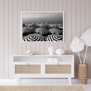 Black and white beach print featuring striped beach umbrellas taken in Nice, France along the Cote dAzur.