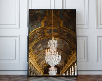 May include: A large, ornate crystal chandelier hangs from a gold and blue painted ceiling in a grand hall. The chandelier is made up of many crystal prisms and bulbs, and it casts a warm glow on the surrounding space.