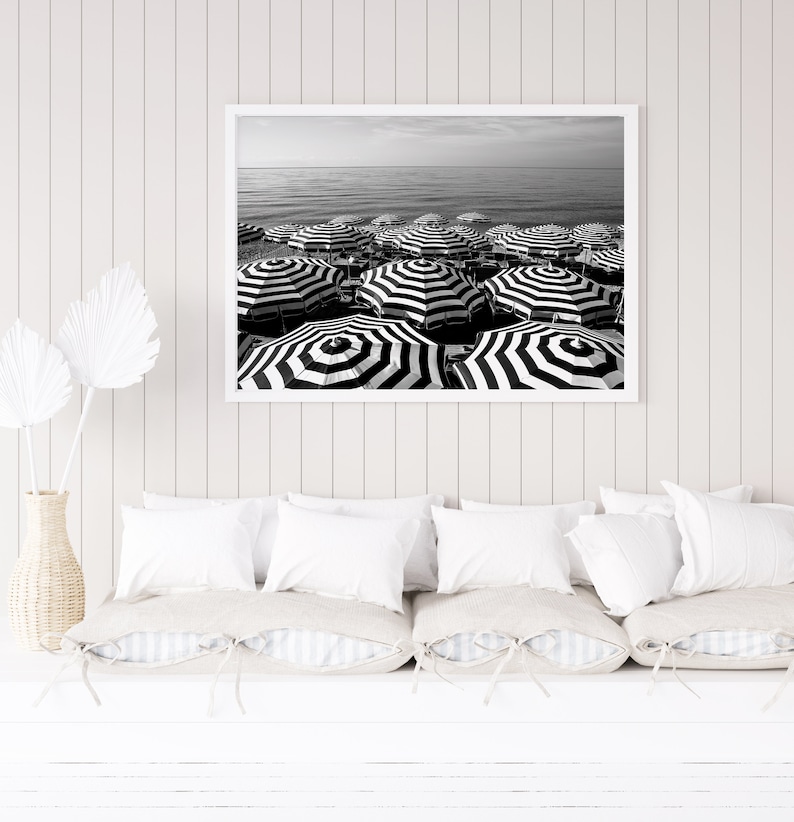 Black and white beach print featuring striped beach umbrellas taken in Nice, France along the Cote dAzur.