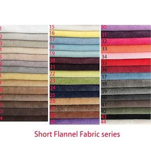 May include: A color chart displaying forty-four swatches of short flannel fabric arranged in three vertical columns. Each swatch is numbered from 1 to 44, showcasing a wide spectrum of colors including neutrals, pastels, and vibrant tones. The text Short Flannel Fabric series is printed at the bottom.