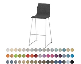 May include: A charcoal gray upholstered bar stool with a high backrest and a slender silver metal frame. Below the stool, there is a grid of seventy-two small circular fabric swatches in various colors and textures, including neutrals, brights, and darks.