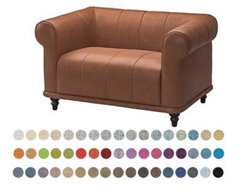May include: A brown leather loveseat with rolled arms and a tufted back. The sofa has black wooden legs and a selection of fabric swatches in various colors below it.