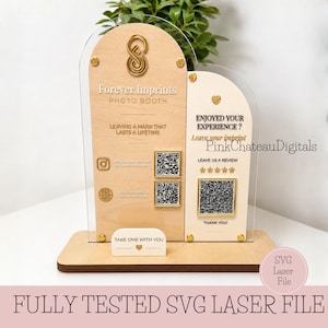 May include: A wooden photo booth sign with clear acrylic accents. The sign features the text "Forever Imprints PHOTO BOOTH" and includes QR codes and social media icons. The sign also has the text "ENJOYED YOUR EXPERIENCE?" and "TAKE ONE WITH YOU".