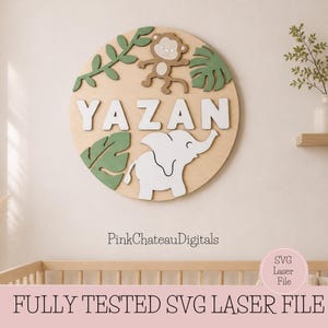 May include: A wooden nursery sign with the name "YAZAN" in white letters. The sign features a monkey, an elephant, and green leaves. The sign is round and has a light wood finish. The text "PinkChateauDigitals" is at the bottom.