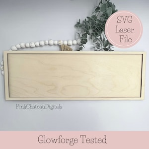 以下が含まれることがあります： 明るい木目仕上げの長方形の木製サイン。サインは細いボーダーで縁取られています。「SVG Laser File」というテキストがピンク色の円の中にあります。「Glowforge Tested」というテキストが一番下にあります。背景には装飾的なビーズと緑があります。