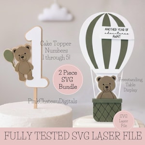 May include: A cake topper with the number 1 and a teddy bear holding a balloon. A hot air balloon with a teddy bear in the basket is also shown. The text reads "Cake Topper Numbers 1 through 5!" and "Another year of adventures await."