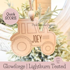 May include: A wooden tractor ornament with the name "JOEY" engraved on it. The ornament is hanging from a twine string with a wooden bead. The text "Quick SCORE" and "Glowforge | Lightburn Tested" are also visible.