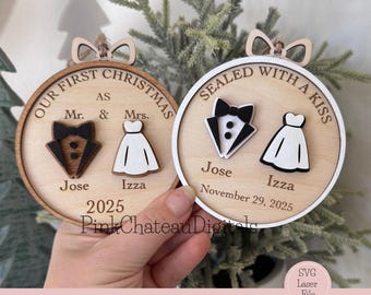 Op de afbeelding: Twee houten kerstversieringen met bruiloftthema's. Eén zegt "Our First Christmas as Mr. & Mrs." met een smoking en jurk. De andere zegt "Sealed with a Kiss" met een smoking en jurk. Namen en data zijn inbegrepen.