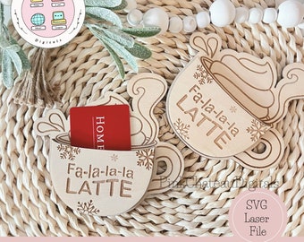 Könnte beinhalten: Zwei Holzausschnitte einer Kaffeetasse mit dem Text "Fa-la-la-la LATTE" auf jeder. Die Ausschnitte befinden sich auf einer geflochtenen Weidefläche. Die Ausschnitte sind für den Laserschnitt konzipiert.